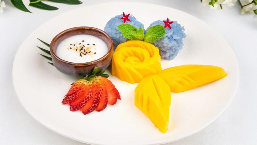 Thai mango sticky rice decorated with carved mango and strawberry
