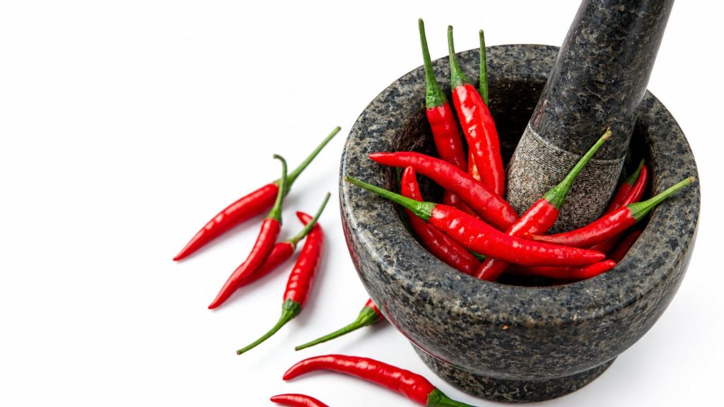 Fresh red Thai chillies in a stone mortar and pestle