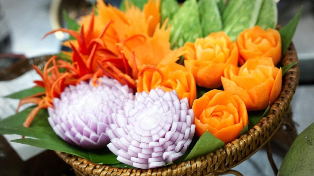 Thai vegetable carving of carrot roses and onion chrysanthemums in a woven basket
